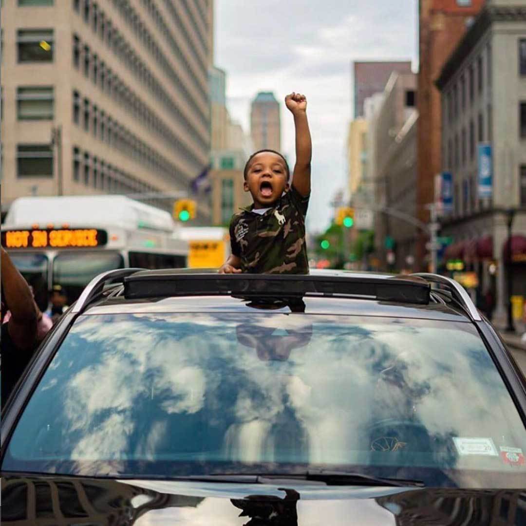 How to Get Your Kids Involved in Activism young boy raising arm in a New York protest